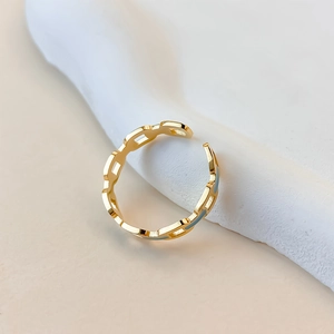 Macro detail of gold geometric chain link ring with blue enamel drips on a stone