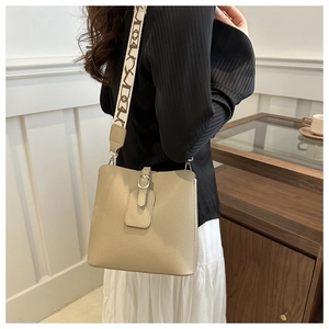 Detail of light khaki leather bucket bag with jacquard letter strap on model