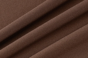 Gros plan détaillé sur un tissu en maille côtelée marron café montrant la texture fine