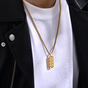 Detail shot of men's gold geometric pendant with industrial tire pattern texture