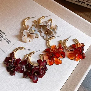 Three pairs of retro floral resin hoop earrings in amber and marble white tones