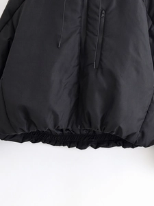 Detail of black tactical puffer jacket hem showing zip closure and elasticated finish