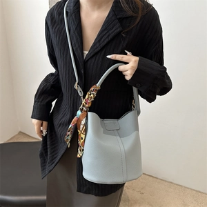 Light blue bucket bag in pebble leather finish with decorative floral silk scarf accessory