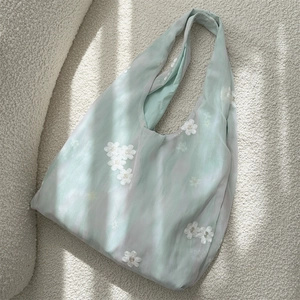 Detail of mint green tote bag featuring white floral embroidery on soft fabric