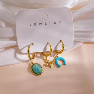 Detail view of 14K gold-plated earring set with turquoise stone, cross, and blue enamel charms