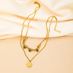 Dettaglio della collana doppia dorata con perline occhio blu e ciondolo a moneta