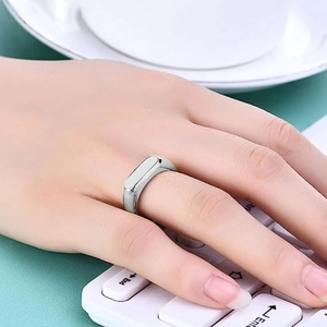 Close-up of polished silver titanium steel ring on finger with office desk background