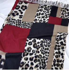 Close-up of leopard print scarf with red color block patchwork and soft tassel detail