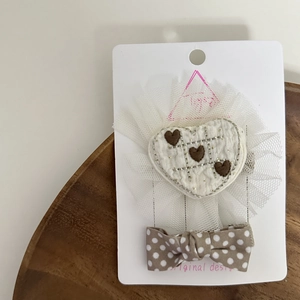 Close-up of quilted heart hair clip and polka dot bow accessory for kids