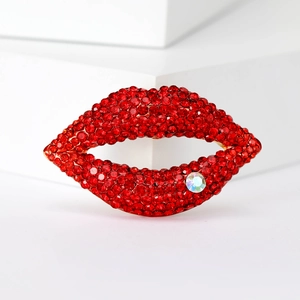 Macro shot of red rhinestone encrusted lip brooch with iridescent crystal on gold base