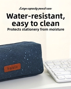 Detail of waterproof navy canvas pencil case with basic leather tag next to keyboard
