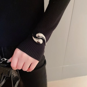 Detail view of a polished silver liquid metal teardrop open cuff bracelet on wrist