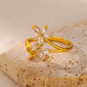 Macro shot of gold flower ring with cubic zirconia and pearls on a stone base