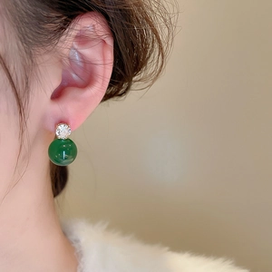 Close-up of elegant dark green pearl drop earring with sparkling zircon on a model