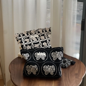 Détail de la broderie papillon sur pochette en toile noire avec étiquette simple wish