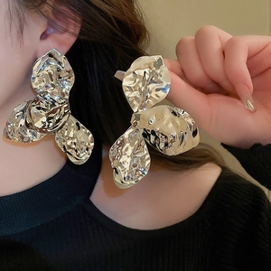 Detail view of silver liquid metal petal earrings on a model with a hammered texture finish