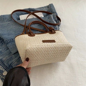 Summer beach straw woven tote bag with brown leather handles and denim jacket background