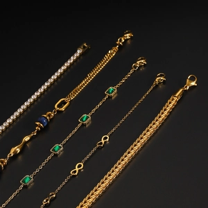 Close-up of five gold-plated stainless steel bracelets with zircon and emerald charms