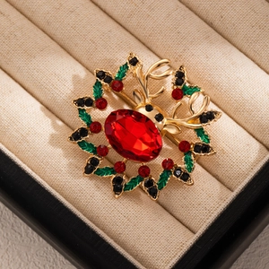 Close-up of a Christmas reindeer brooch with red gemstone and green enamel wreath