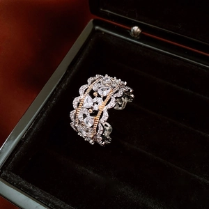 Macro shot of silver and gold lace ring with zircon inlays on black velvet
