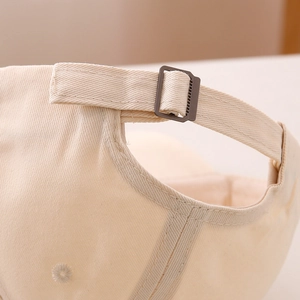 Dettaglio della fibbia in metallo regolabile e del cotone beige del cappellino bimbo