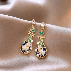 Close-up of vintage pipa-shaped earrings with green enamel and pearls on silk