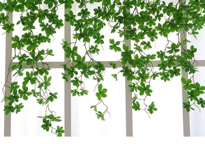 Close-up of artificial hanging vines with lush green leaves draped over a white window
