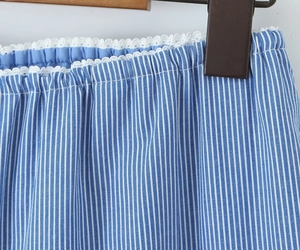 Nahaufnahme von blau-weiß gestreiftem Stoff mit weißer Spitze und detaillierten Nähten