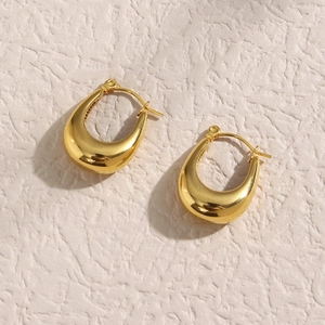 Polished hollow gold teardrop U-shaped earrings on beige textured background