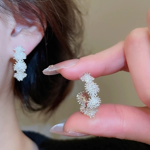 Macro detail of silver plated floral stud earring with layered zircon petals on earlobe