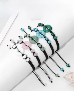 Detail of five handmade braided bracelets with various natural gemstone donut charms