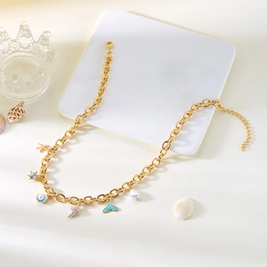 Macro detail of ocean charm necklace with starfish shell and pearl on white tray