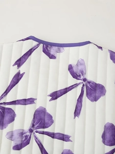 Detail of white quilted coat featuring purple bow print and contrast piping collar