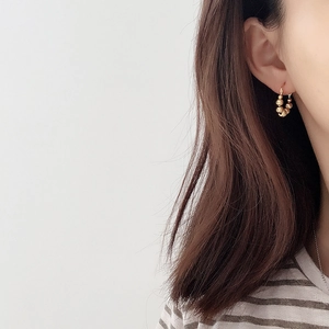 Close-up of minimalist golden beaded hoop earrings worn by a model for a stylish look