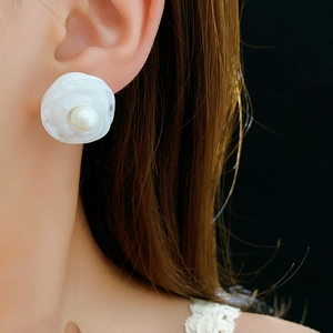 Close-up of elegant floral pearl earring worn by a model with a black background