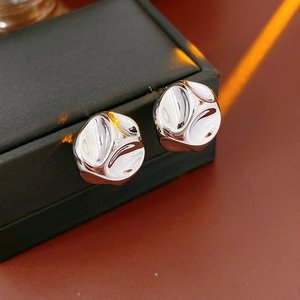 Detailed close-up of silver earrings featuring irregular hammered texture and metallic luster