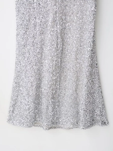 Détail de sequins argentés scintillants et de coutures fines sur une robe à paillettes