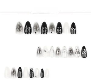 Vue détaillée d'ongles 3D effet marbre noir avec nœuds argentés et perles chic
