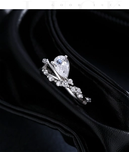 Close-up of pear-cut diamond and V-shaped band rings on black leather background