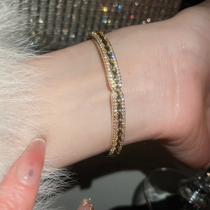 Gros plan d'un bracelet géométrique plaqué or avec zircons pavés et motif tressé