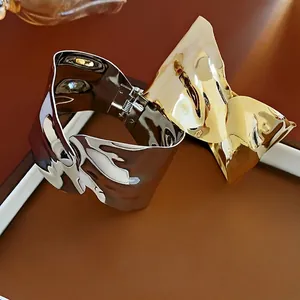 Irregular textured gold and silver cuff bracelets on a brown leather surface