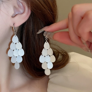 Detail of layered teardrop sequins earrings with pearlescent finish on model