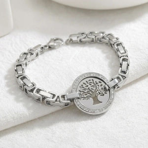 Detailed view of silver tree of life bracelet with sparkling crystals on white fabric