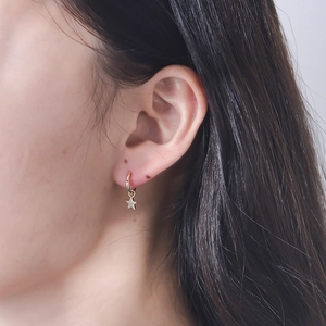 Close-up of elegant gold star drop earrings with sparkling pavé zircons on a model