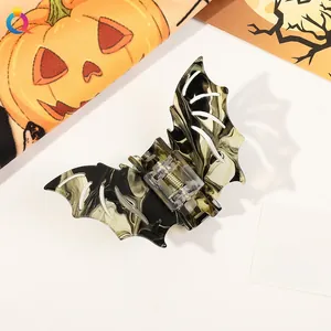 Close-up of marble pattern bat hair claw clip with Halloween pumpkin background decor