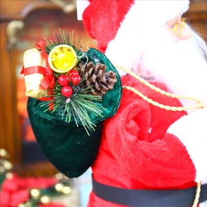 Detail of Santa Claus decoration featuring a velvet gift bag with pine cones and berries