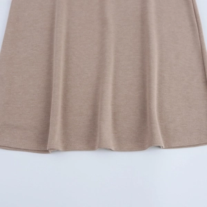 Detailed macro view of light brown knit fabric texture and hem stitching on the skirt