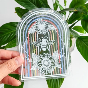 Detailed view of an arched suncatcher sticker featuring sunflowers and a bee on glass