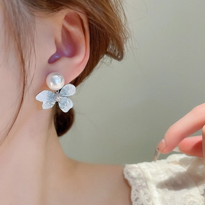 Close-up of sweet butterfly stud earring with artificial pearl and rhinestone details