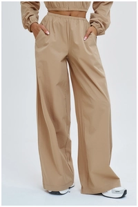 Detail of high-waisted loose sports trousers with side pockets and elastic waistband